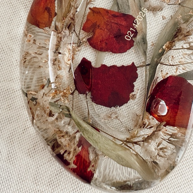 Close-up of red rose petals and gold flakes inside a resin trinket tray