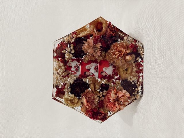 Large hexagonal resin block filled with preserved red, peach, and cream flowers around wedding photos