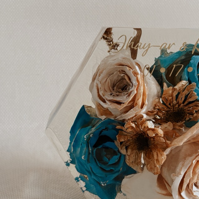 Close-up of preserved roses and gold engraving inside a hexagonal resin block