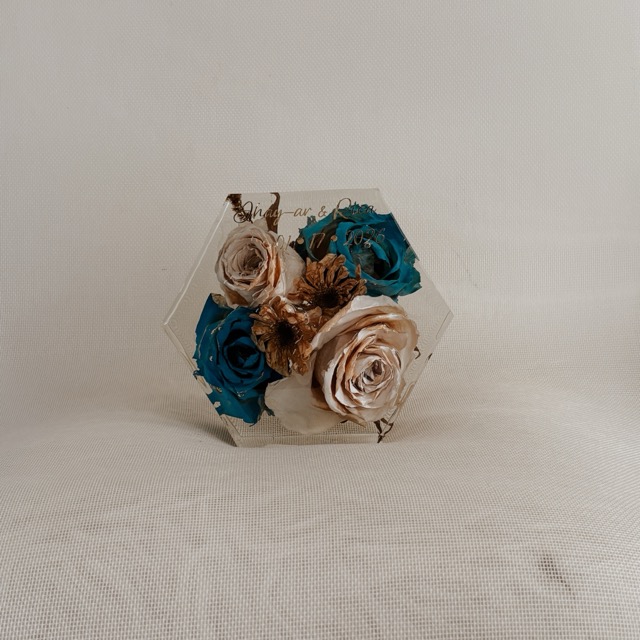 Front view of a hexagonal resin block with cream and teal preserved roses