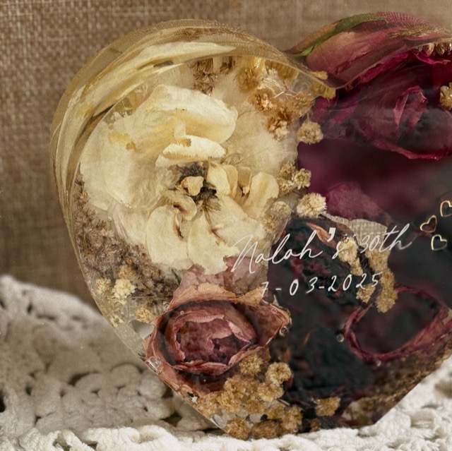 Close-up of a cream flower and burgundy roses inside a heart-shaped resin piece