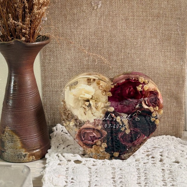 Heart-shaped resin piece styled beside a ceramic vase on a lace cloth